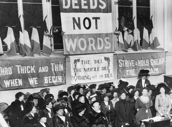 Historical photograph of a women's suffrage rally with banners and women in the audience.