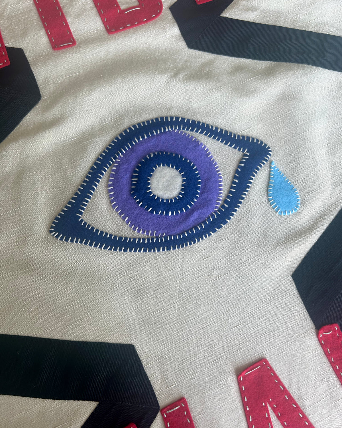 Close-up of banner with a large embroidered eye design on a white background